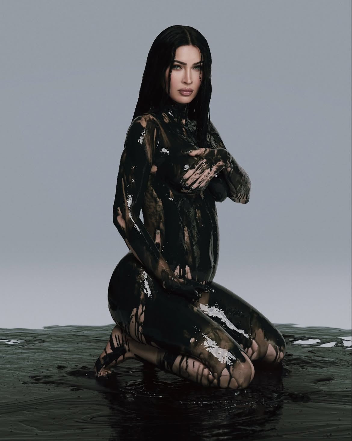 Megan Fox maternity portrait with glossy black paint against a gray backdrop